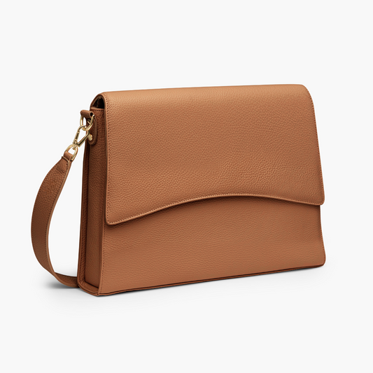 A laptop bag in caramel color with grained leather and light gold metalware. It has a detachable shoulder strap. 