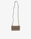A taupe leather crossbody bag with a long, thin strap, shown against a plain off-white background.