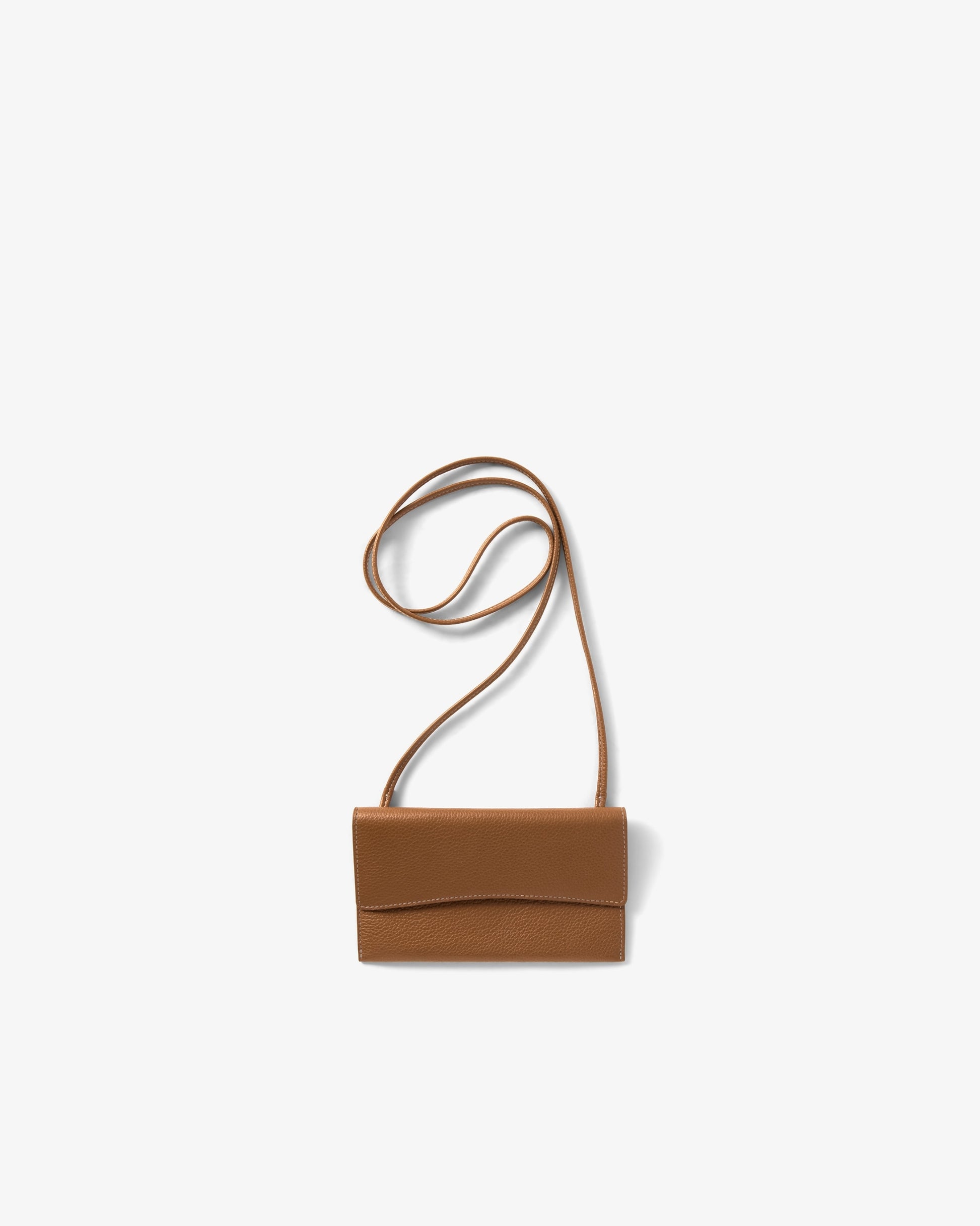 A small tan leather crossbody bag with a long thin strap, shown against a plain light gray background.