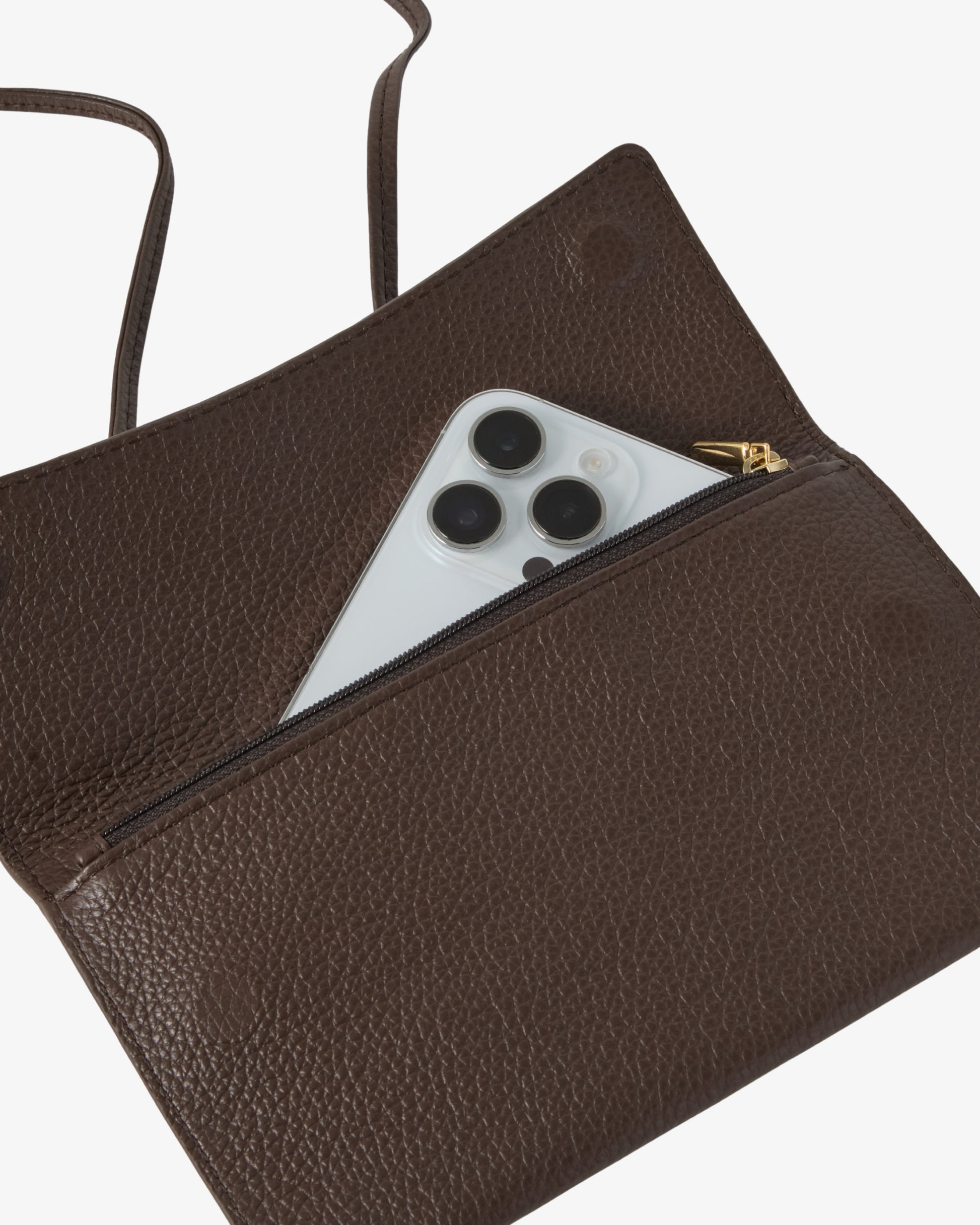 A close-up of a dark brown pebbled leather clutch or pouch with a zippered pocket, shown open with a silver smartphone partially tucked inside. A thin brown strap is visible at the top left against a clean white background.