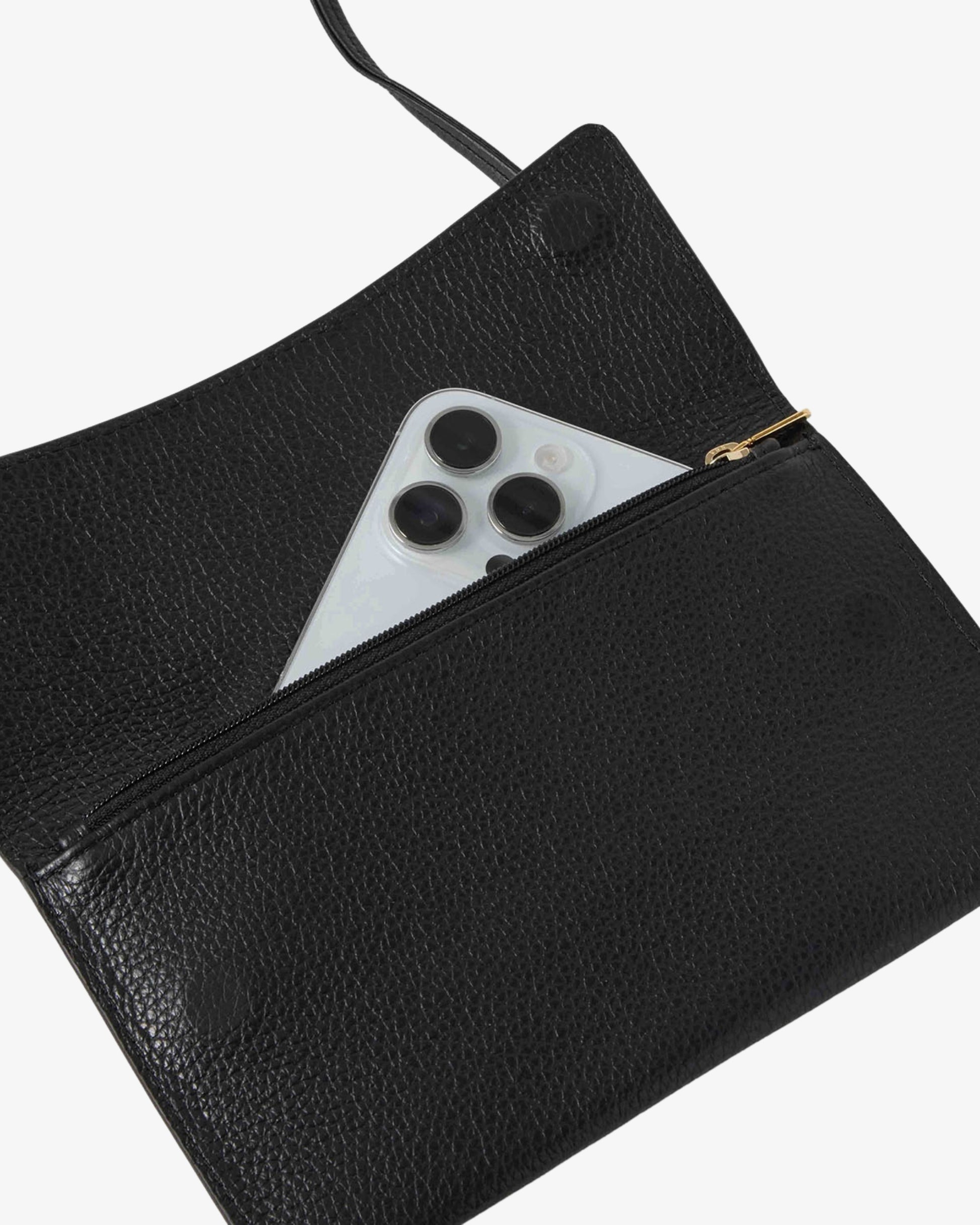 A close-up of a black pebbled leather pouch with a gold zipper, shown with a silver smartphone partially tucked into the zip pocket against a light gray background.