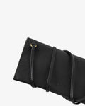 Close-up of a black pebbled leather clutch bag with a strap and gold-tone ring detail, shown against a plain white background.