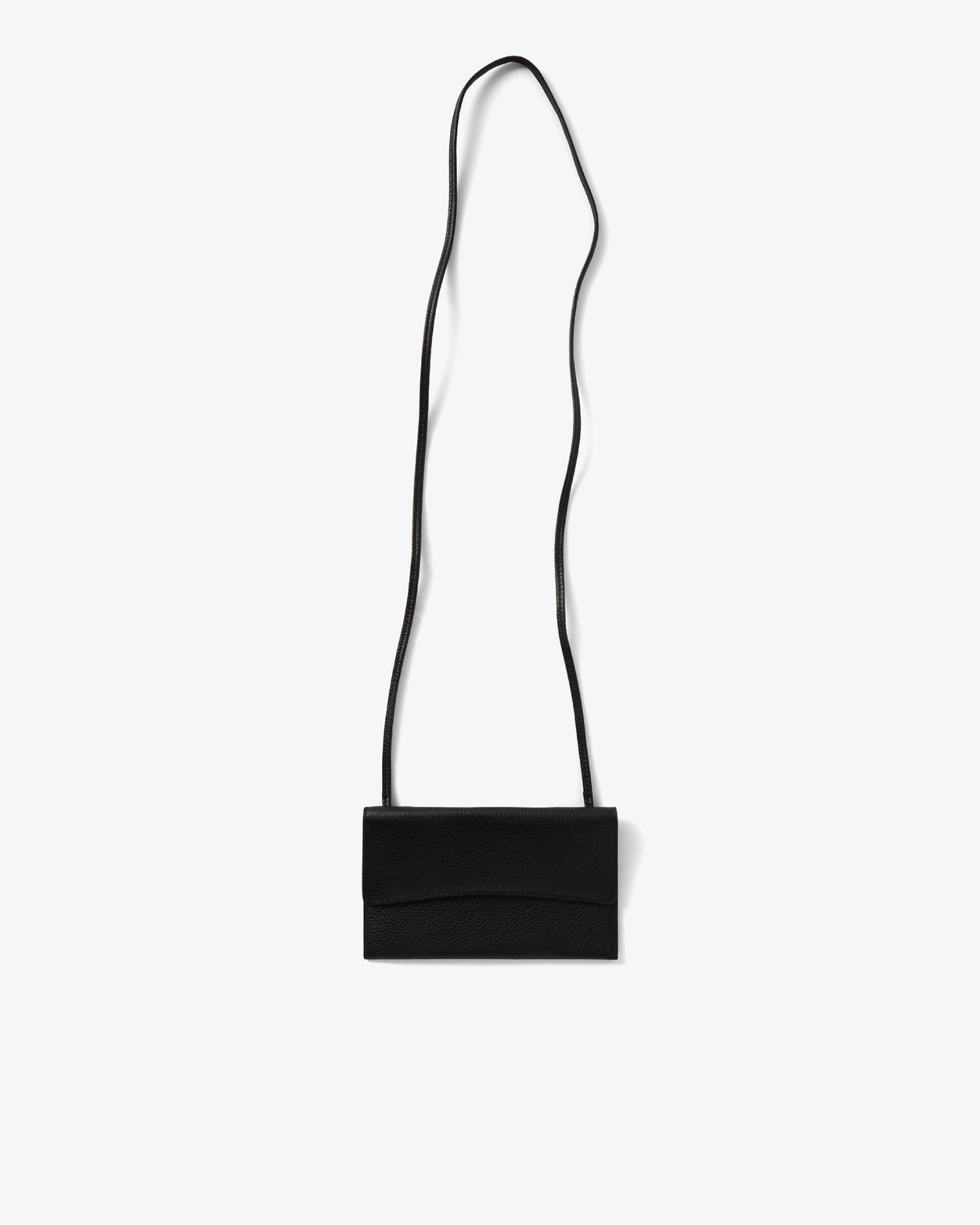 A minimalist black leather crossbody bag with a slim, long strap, shown against a plain light gray background.