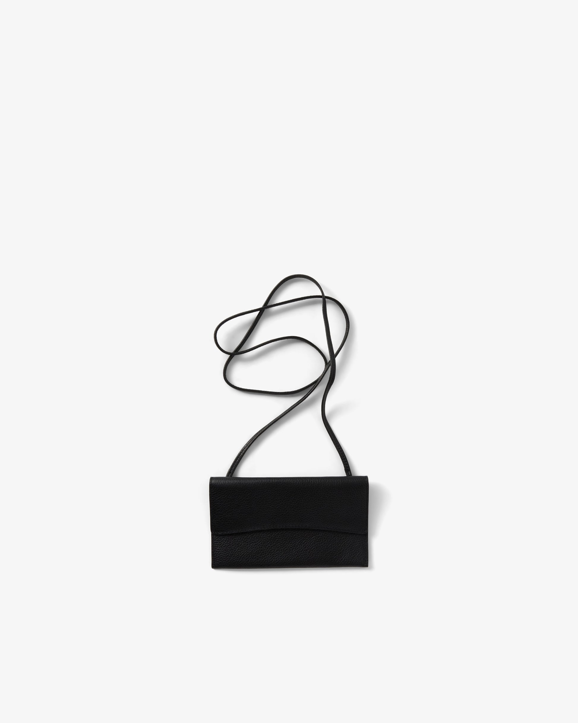 A minimalist black envelope-style bag with a thin black shoulder strap, photographed flat on a clean white background.