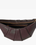A close-up of a pleated leather bag in dark  brown, showing the interior with gold zippers against a light gray background.