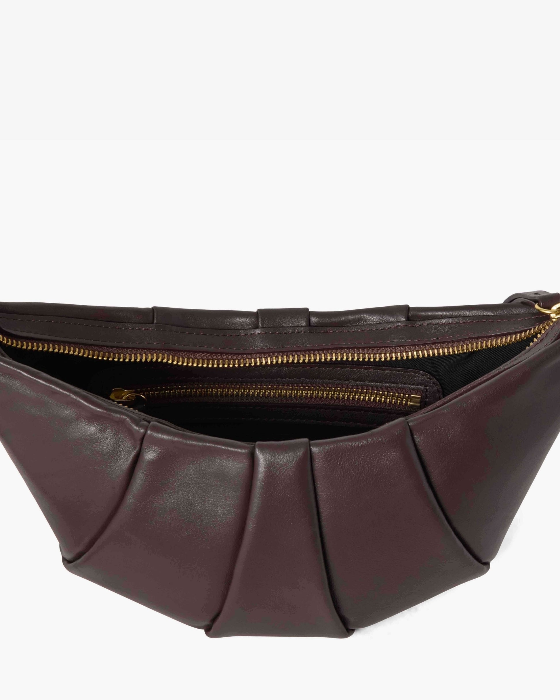 A close-up of a pleated leather bag in dark  brown, showing the interior with gold zippers against a light gray background.