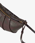 A close-up of a dark brown leather shoulder bag with pleated detailing, a gold zipper, and a matching leather strap against a light gray background.