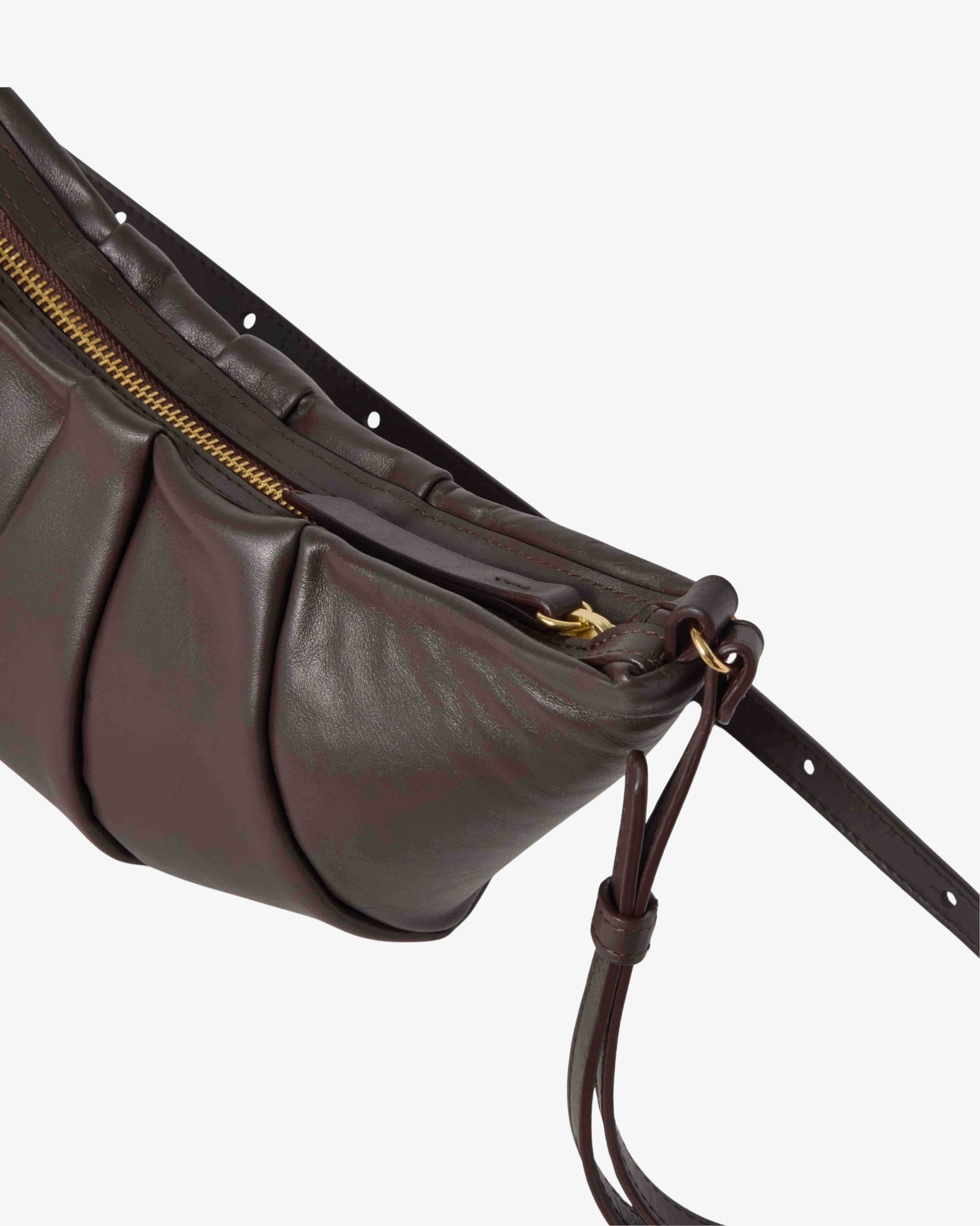 A close-up of a dark brown leather shoulder bag with pleated detailing, a gold zipper, and a matching leather strap against a light gray background.