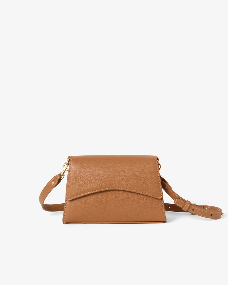A tan leather crossbody bag with a curved flap and a matching adjustable shoulder strap, shown against a plain white background.