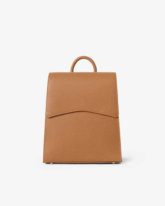 A tan leather backpack with a top handle, shown from the front against a plain white background.