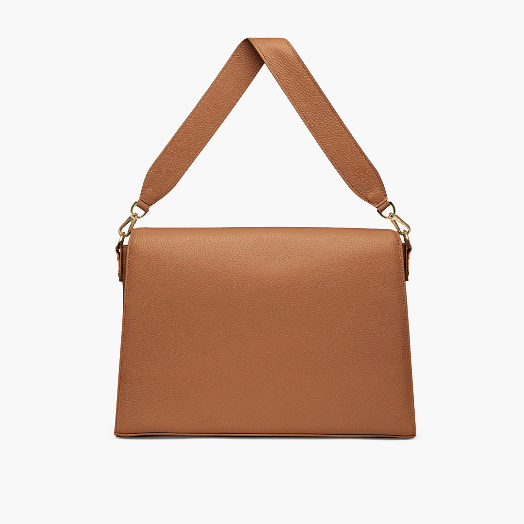 A laptop bag in caramel color with grained leather and light gold metalware. It has a detachable shoulder strap. 