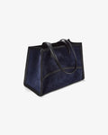 A navy blue suede tote bag with black leather trim and handles, shown from a three-quarters angle on a light gray background.