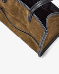 Close-up of a brown suede tote bag with black leather trim and handles, shown on a clean white background.