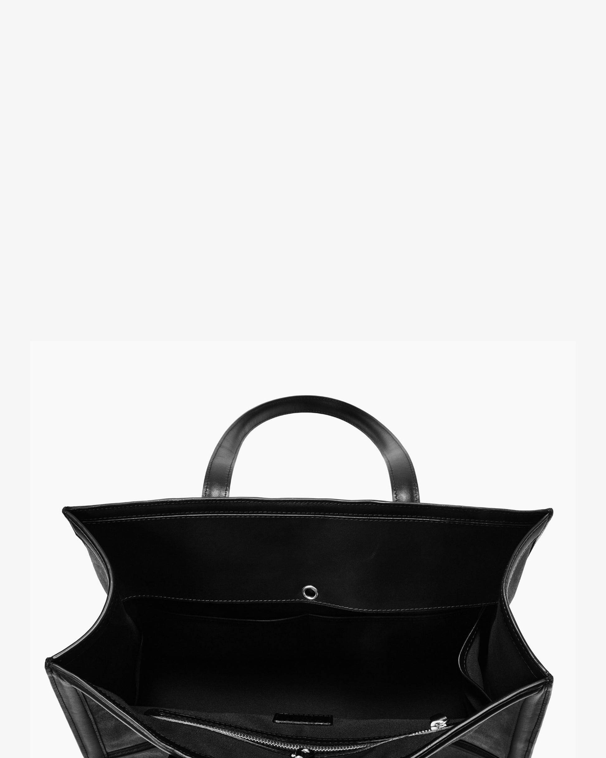 Black leather tote bag shown from a top-down view, highlighting its spacious interior, double top handles, and zippered compartments against a plain white background.