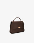 A dark brown leather handbag with a top handle and a small gold-tone metal accent on the front, shown against a plain white background.