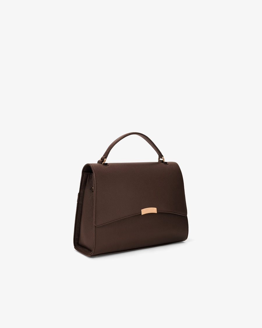 A dark brown leather handbag with a top handle and a small gold-tone metal accent on the front, shown against a plain white background.