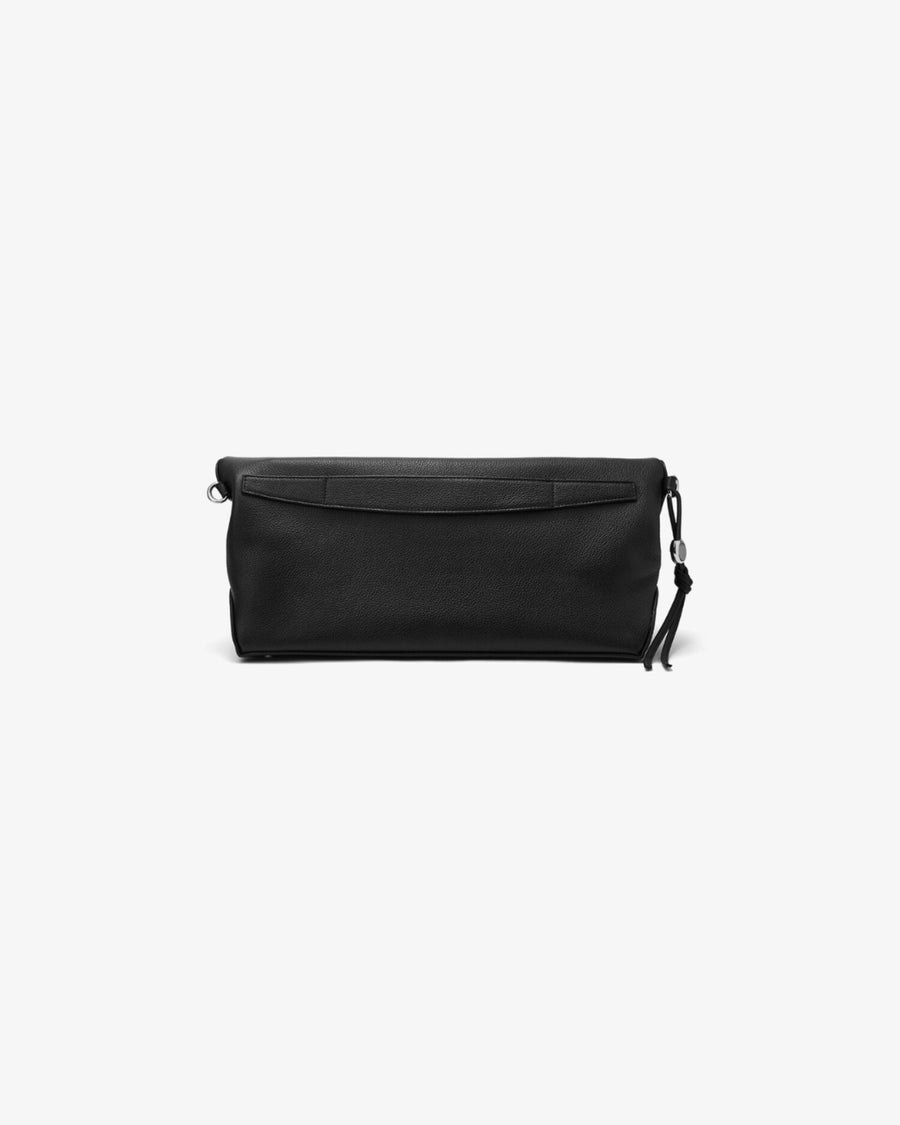 A black leather bag with a flap closure and a small tassel detail on the side, and a luggage strap on the back, photographed against a solid white background.