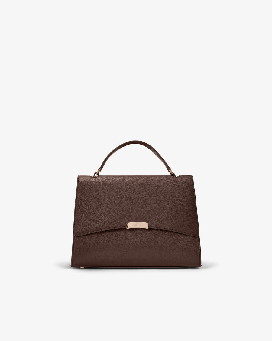 A structured dark brown leather handbag with a top handle and a small gold-tone metal accent on the front flap, shown against a plain light gray background.