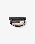 An open black leather bag with gold-tone hardware, shown from a top-down view on a light gray background. Inside, a brown leather zippered pouch, a white notebook, and a small white accessory are neatly arranged.