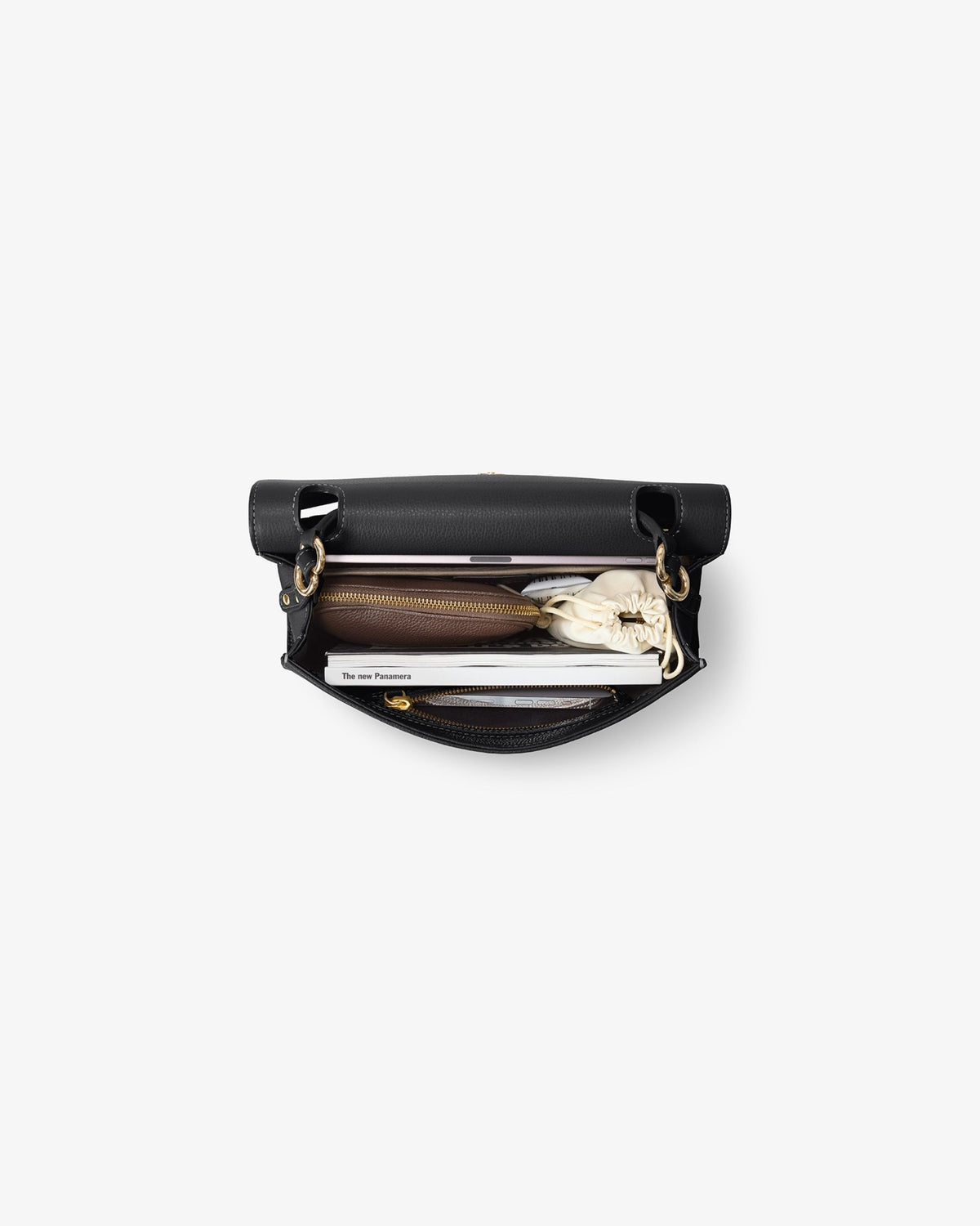 An open black leather bag with gold-tone hardware, shown from a top-down view on a light gray background. Inside, a brown leather zippered pouch, a white notebook, and a small white accessory are neatly arranged.