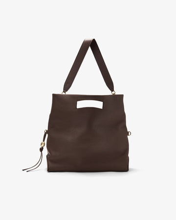 A dark brown leather tote bag with a top handle, a rectangular cutout on the front, and a small tassel detail on the side, shown against a plain light gray background.