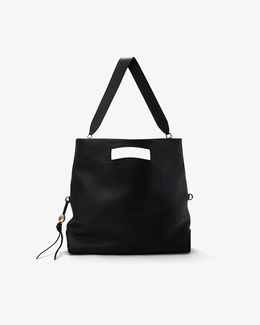 A black leather shoulder bag with a top handle, a rectangular cutout detail on the front, and a small hanging tassel charm, shown against a plain light gray background.