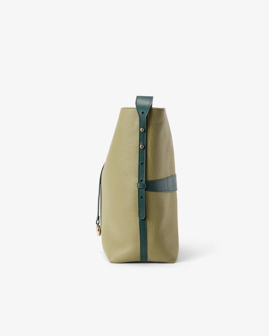A structured leather bucket bag in sage green and teal, featuring a vertical strap closure with gold-tone hardware, photographed against a clean white background.