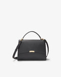 A black textured leather handbag with a top handle, a detachable shoulder strap, and a small gold-tone metal plaque on the front flap, shown against a plain white background.