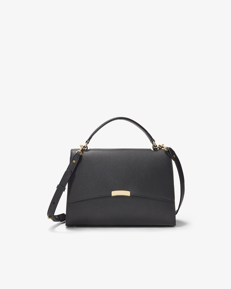 A black textured leather handbag with a top handle, a detachable shoulder strap, and a small gold-tone metal plaque on the front flap, shown against a plain white background.