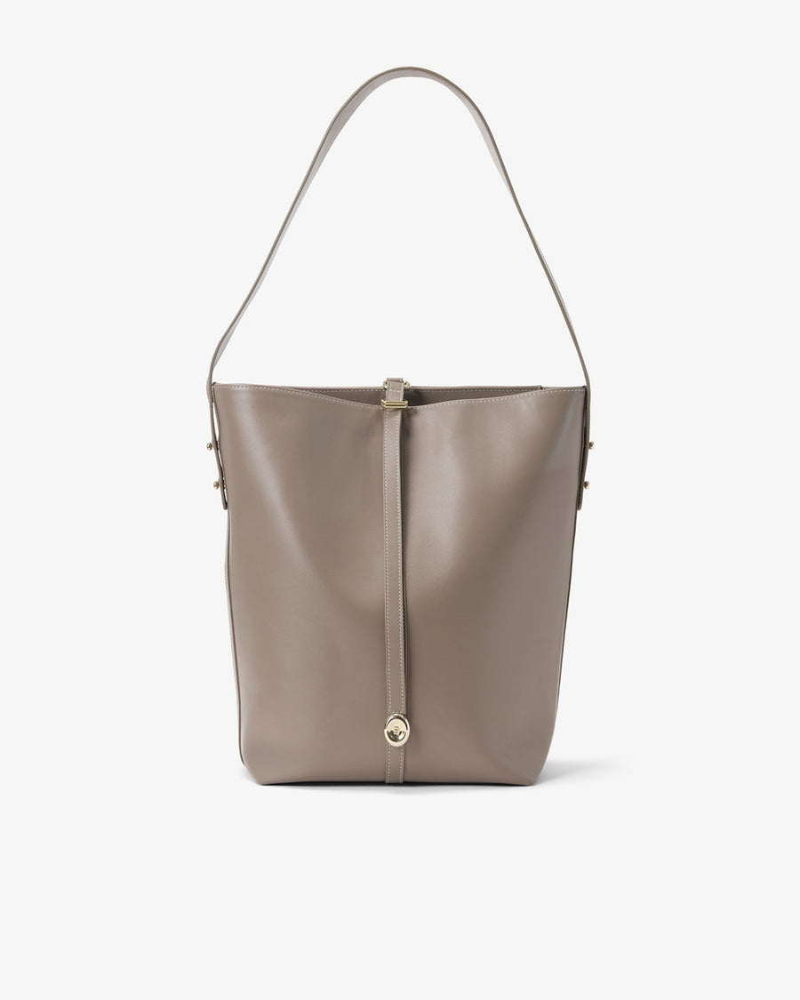 A taupe leather bucket bag with a single shoulder strap and a central hanging strap detail secured by a gold-tone button, shown against a plain white background.