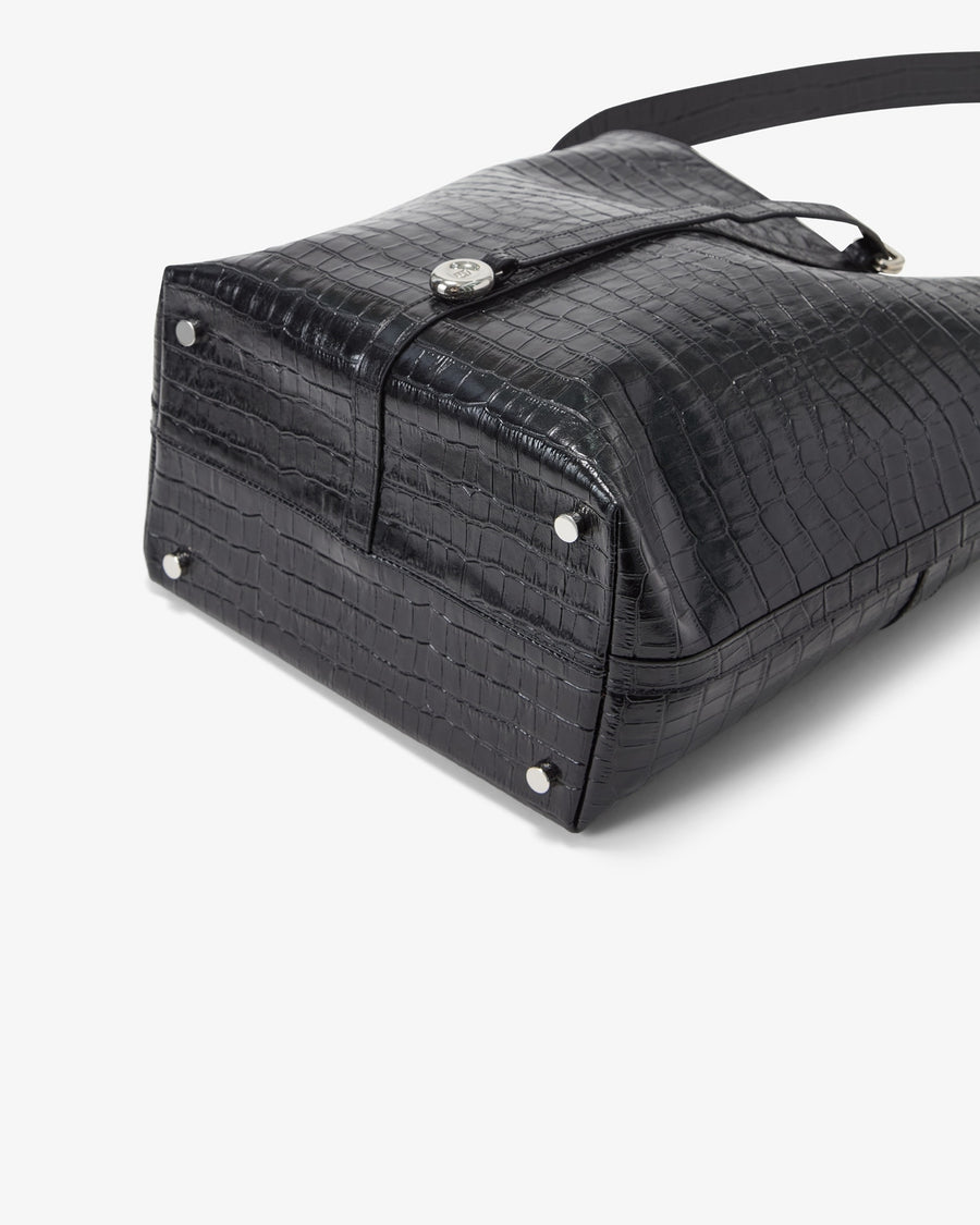 Close-up of a black crocodile-embossed leather bag with silver-tone hardware and a strap, photographed on a clean white background.