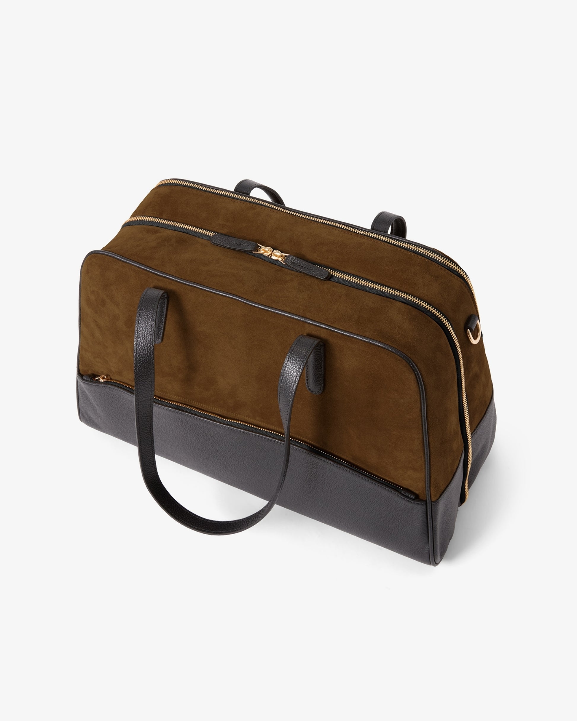 A brown and black duffel bag with a suede-like upper body and a smooth black leather base, featuring dual top handles and a top zipper closure, shown on a light gray background.