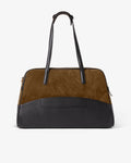 A color-blocked leather and suede duffel bag with a brown suede upper section, a black leather lower section, and a luggage strap and black leather handles, shown against a plain white background.