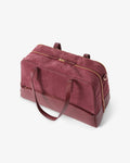 A burgundy suede duffel bag with dark maroon leather handles and gold-tone zipper accents, photographed on a clean white background.