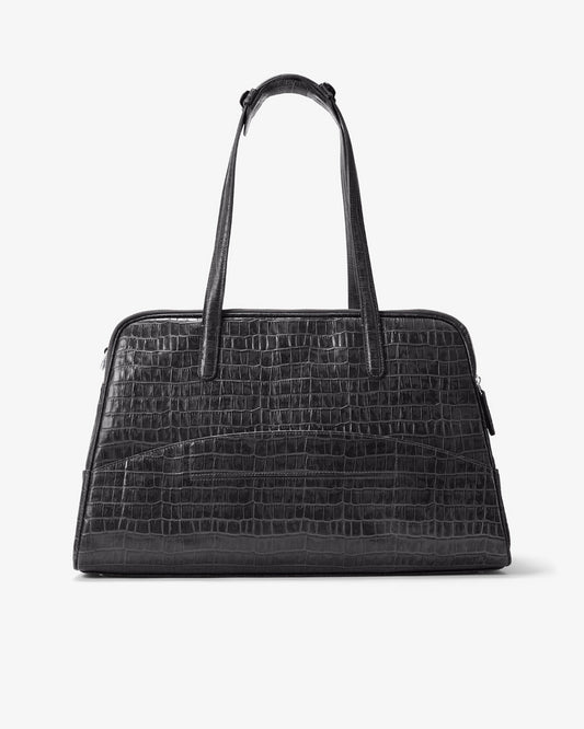 A black crocodile-embossed leather handbag with dual top handles and a luggage strap, shown against a plain white background.