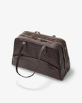 A dark brown crocodile-embossed leather duffel bag with a top zipper, side zipper, and a shoulder strap, shown on a light gray background.