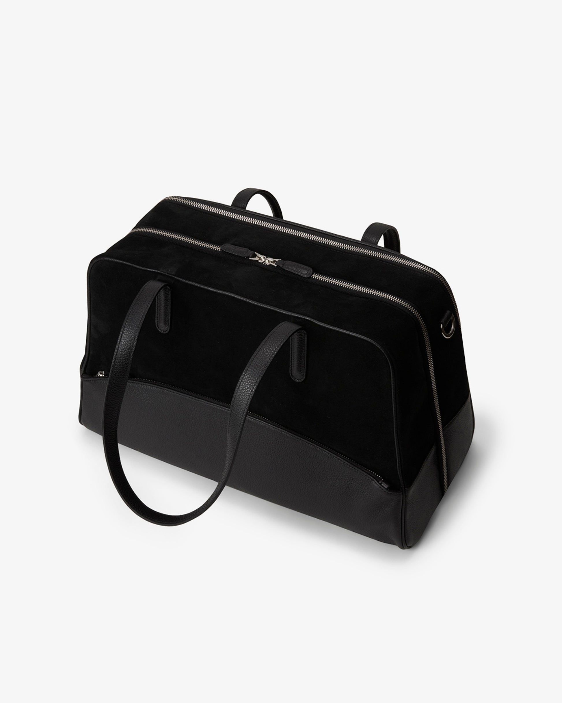 A black duffel bag made of leather and suede, with dual top handles and a shoulder strap, photographed on a clean white background.