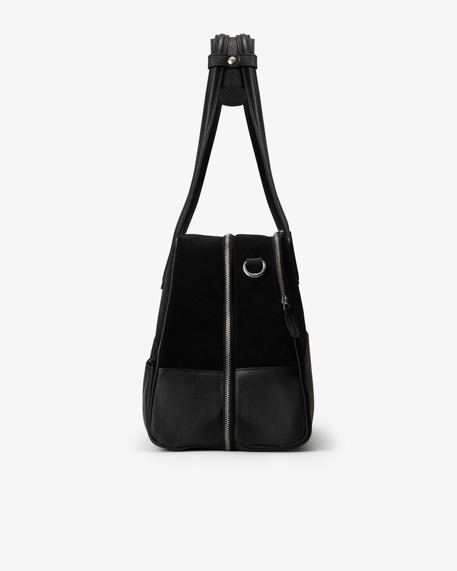 A black shoulder bag with a black suede upper body, black leather lower front pocket, and a black shoulder strap, shown against a plain white background.