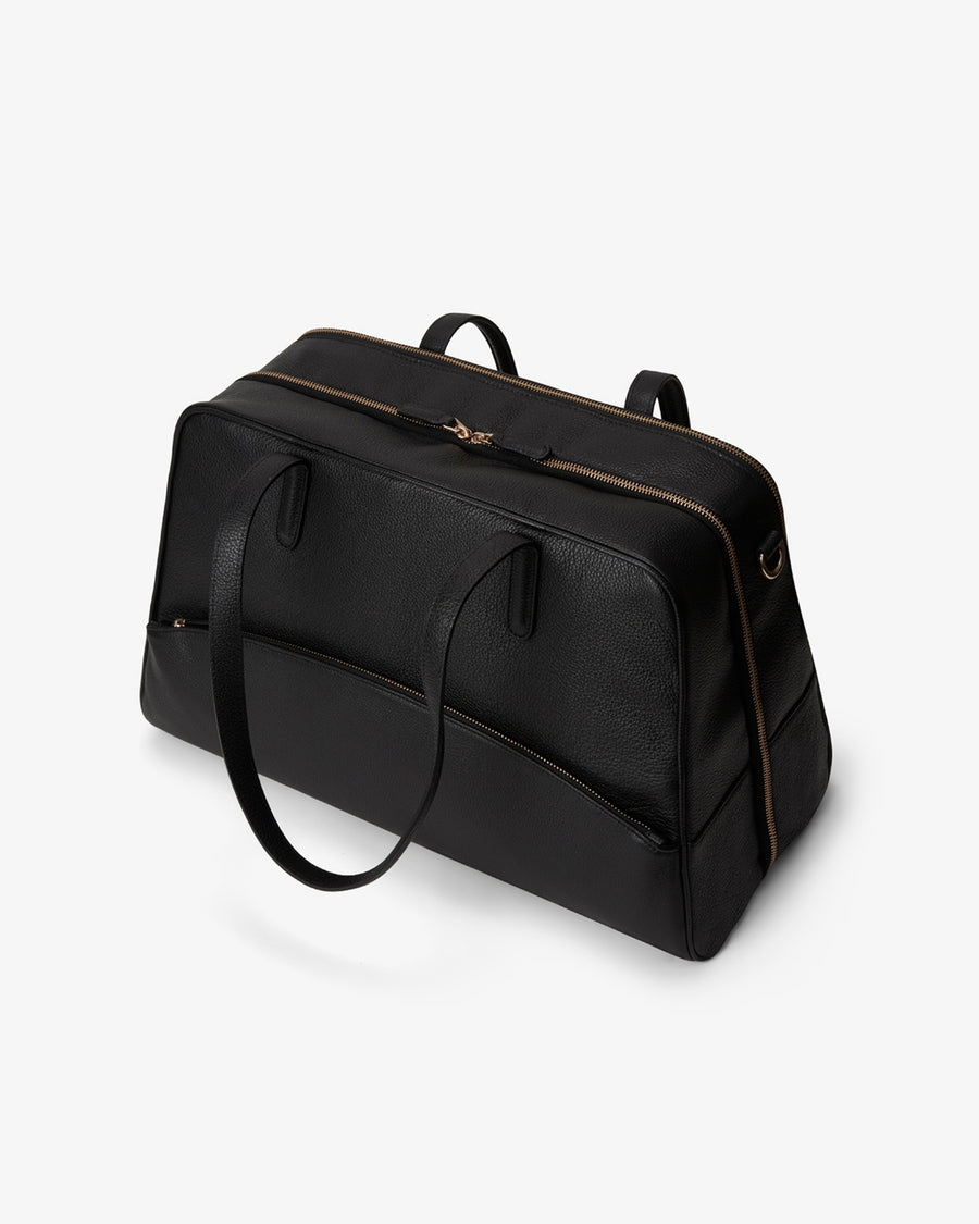 A black leather duffel bag with gold-tone hardware and dual shoulder straps, photographed on a clean white background.