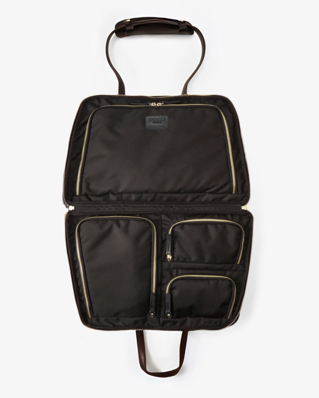 An open black nylon bag with multiple interior pockets, gold-tone zippers, and dark brown leather handles, shown against a light gray background.
