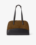 A color-blocked duffel bag featuring a brown suede upper body, a black leather lower base, and black leather shoulder straps, shown against a plain white background.