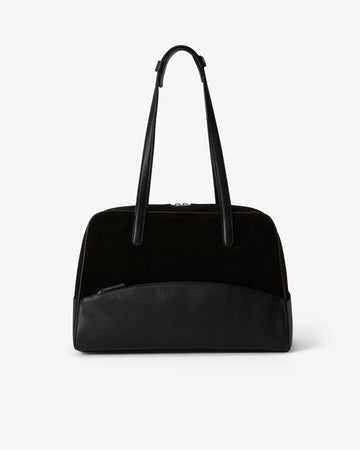 A black shoulder bag with a smooth leather base, a black suede upper section, and dual top handles, shown against a plain light gray background.