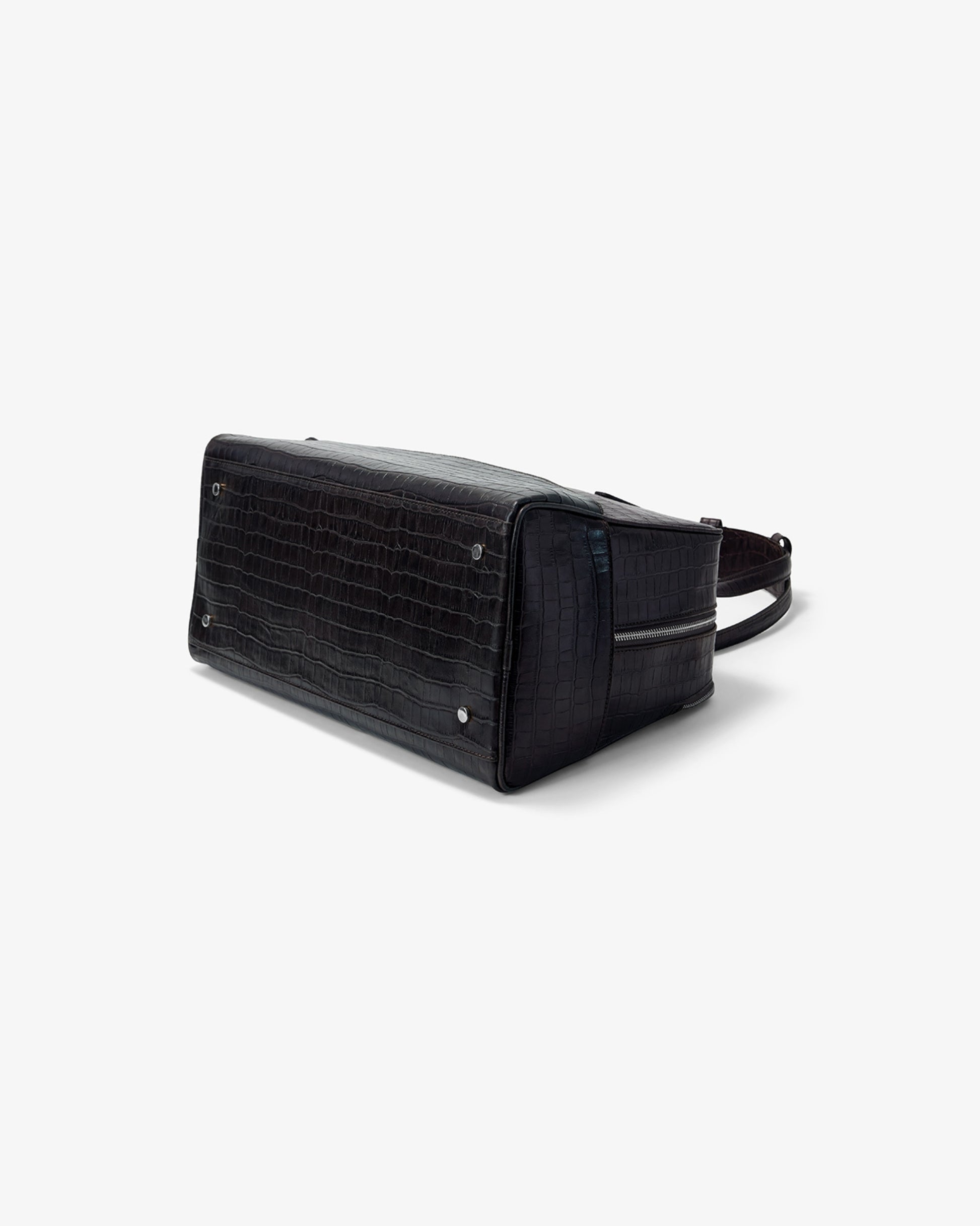 A black crocodile-embossed leather shoulder bag with a zippered top and side pocket, shown from a three-quarters angle on a light gray background.
