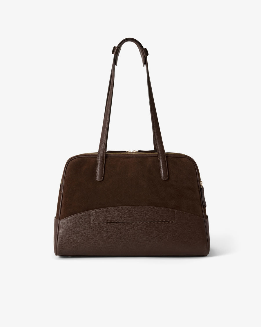 A dark brown leather handbag with a structured dome shape, featuring a back horizontal panel with a luggage strap, a top zipper closure, and two shoulder straps, photographed against a clean white background.