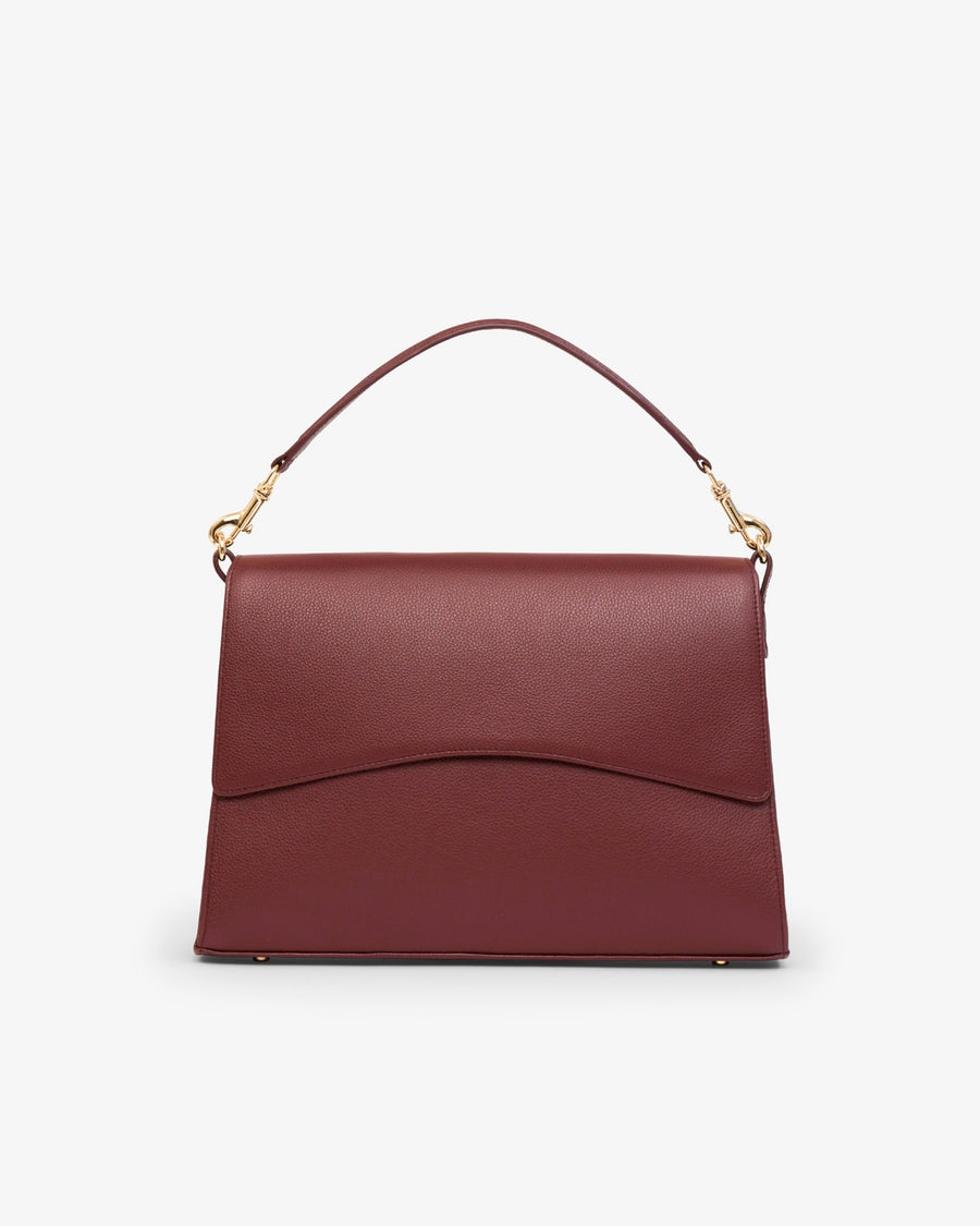 A structured burgundy leather handbag with a top handle, gold-tone hardware, and a curved flap closure, shown against a plain white background.