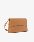 A tan leather shoulder bag with a curved flap and a matching shoulder strap, shown on a plain light gray background.