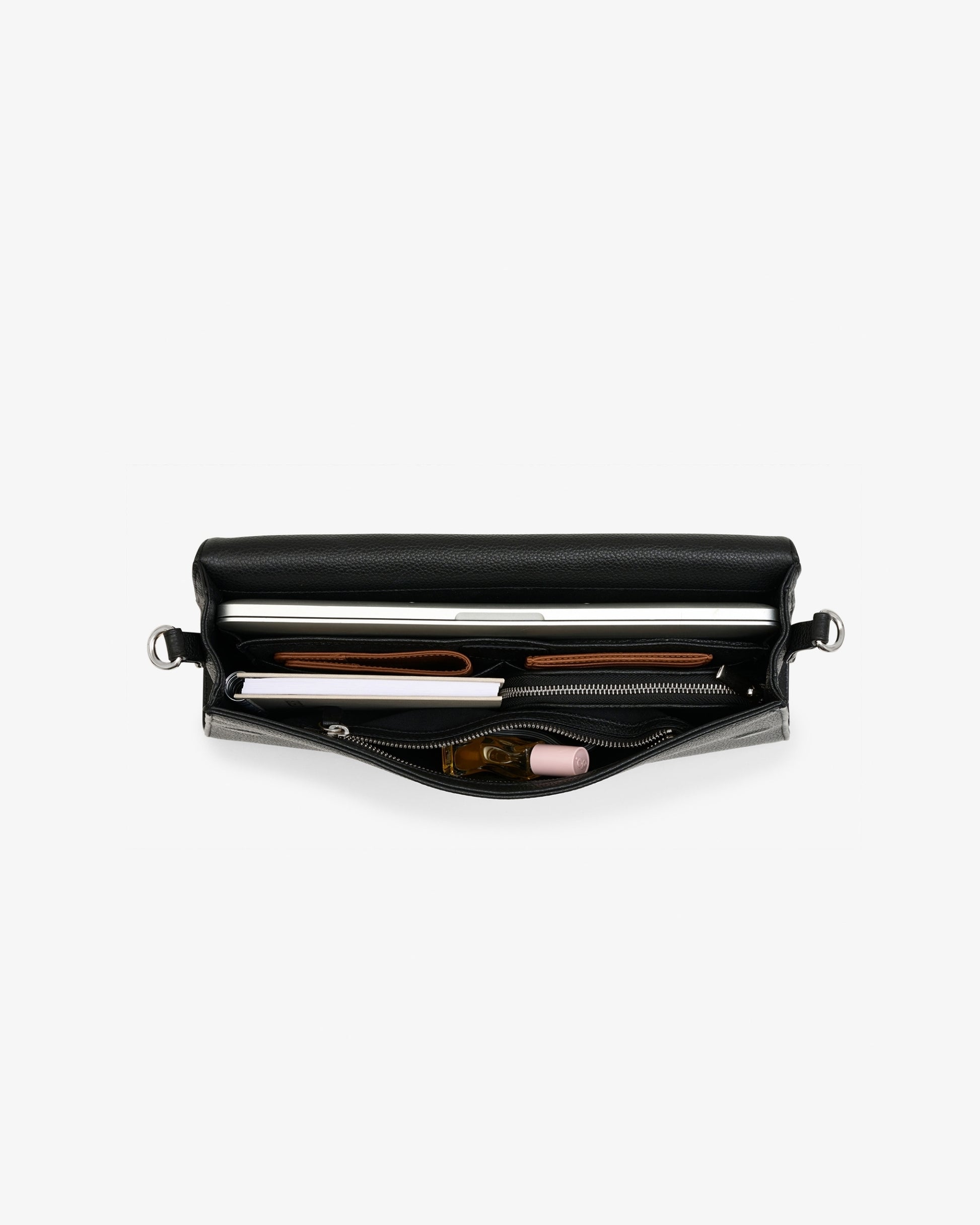 A black leather bag shown open, displaying its interior compartments filled with a silver laptop, a brown leather strap, a white pen, and a small pink item, set against a plain light gray background.