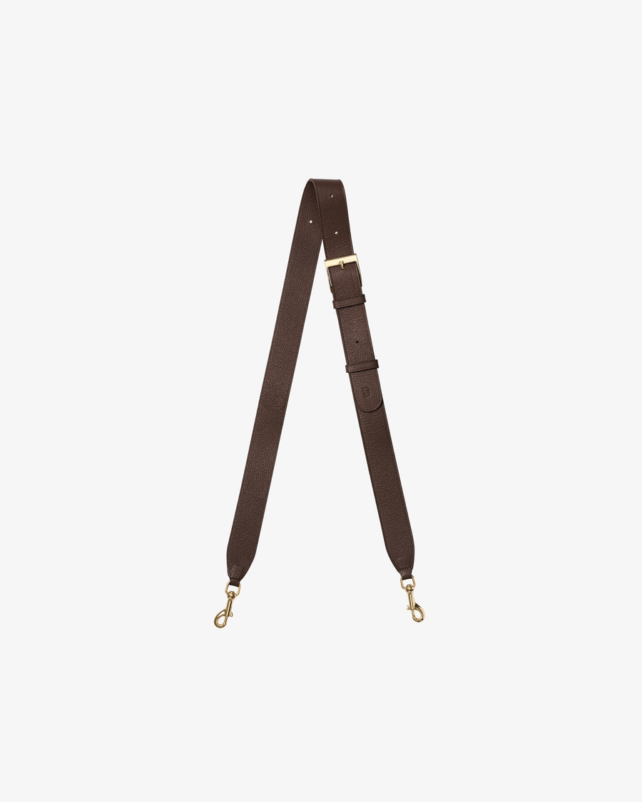A dark brown leather cross body strap with gold-tone metal hardware, including a buckle, adjustment loops, and two swivel snap hooks, displayed on a light gray background.