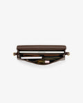 A brown leather  bag shown open from a top-down view, revealing its interior compartments filled with travel accessories like a a passport holder, a pen, and a small pouch, set against a plain light gray background.
