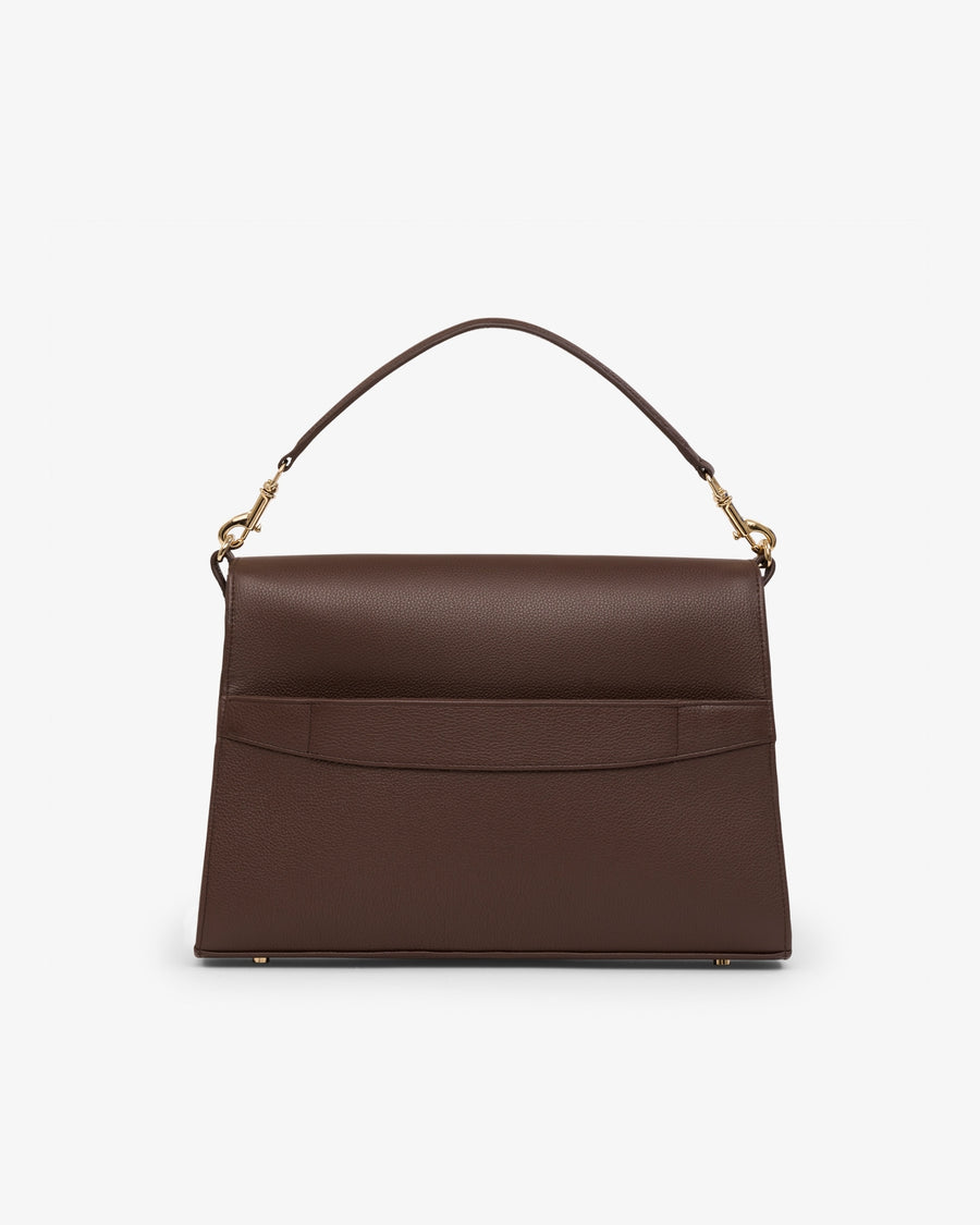 A structured dark brown leather handbag with a top handle, gold-tone hardware, and a luggage strap, shown against a plain light gray background.